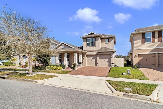 craftsman-style house featuring a front lawn, decorative driveway, an attached garage, and stucco siding