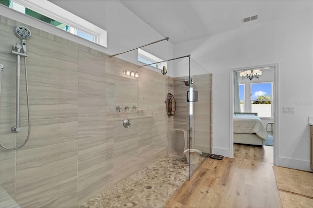 ensuite bathroom featuring ensuite bathroom, wood finished floors, visible vents, baseboards, and tiled shower