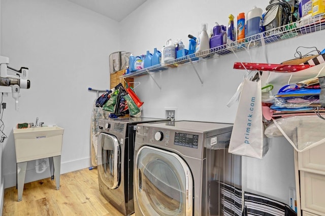 clothes washing area with washer and dryer, laundry area, baseboards, and light wood finished floors