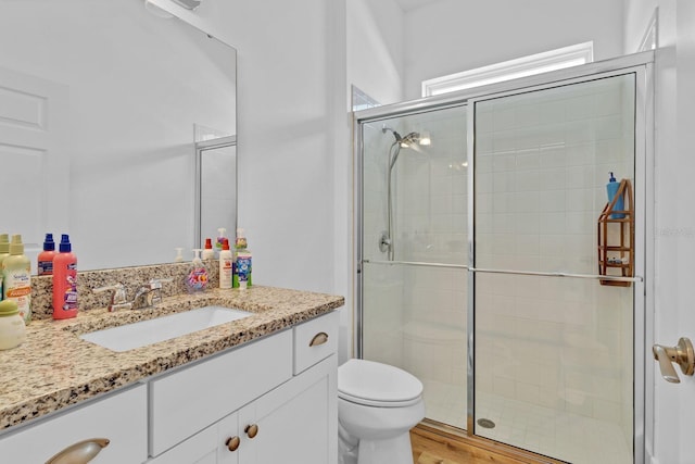 bathroom with toilet, a stall shower, and vanity