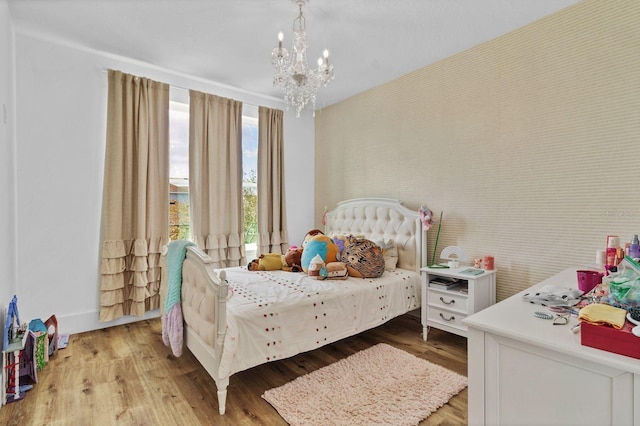 bedroom with wallpapered walls, a notable chandelier, and wood finished floors