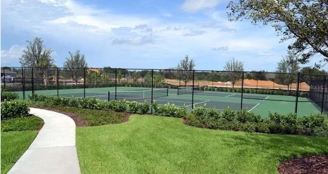 view of tennis court with fence and a lawn