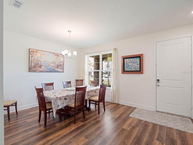 dining room featuring dark wood-style floors, a chandelier, visible vents, and baseboards