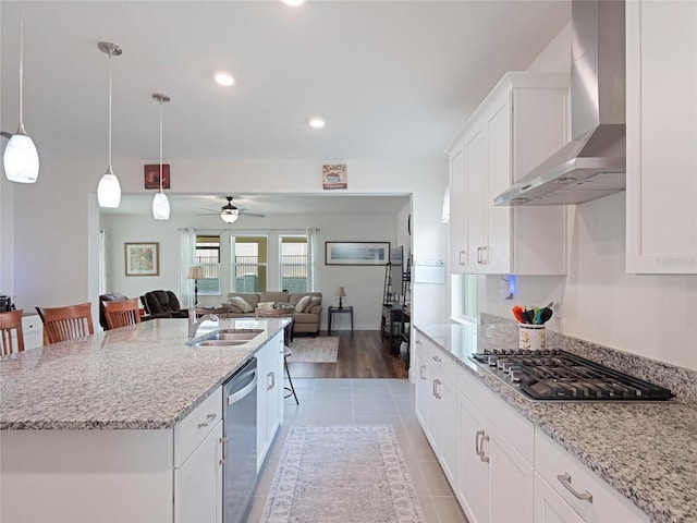 kitchen featuring stainless steel appliances, a breakfast bar, open floor plan, wall chimney exhaust hood, and an island with sink