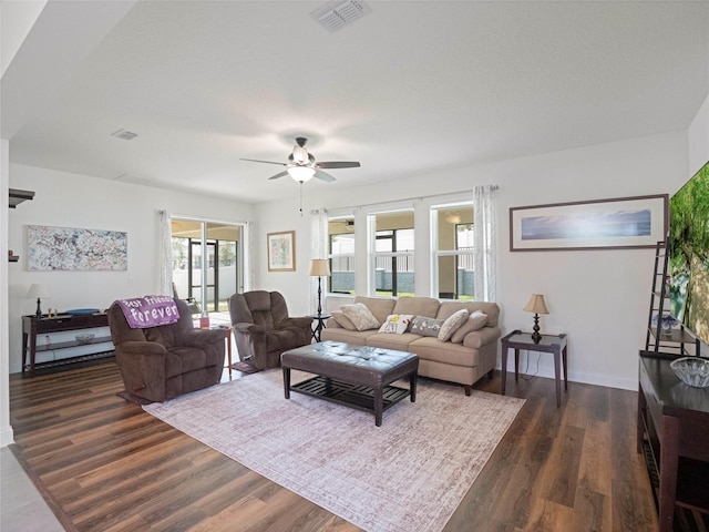 living area with dark wood-style flooring, visible vents, and ceiling fan