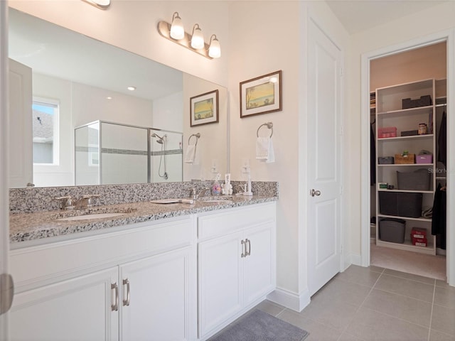 full bathroom with double vanity, a stall shower, a sink, and tile patterned floors