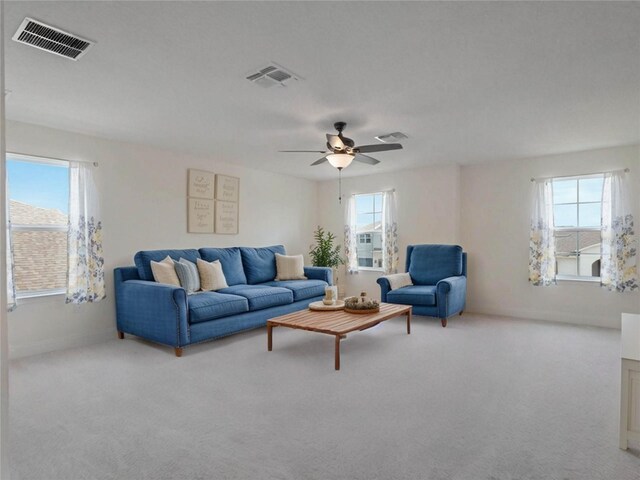 living area with a ceiling fan, visible vents, and light colored carpet