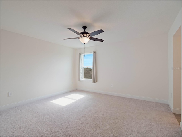 unfurnished room with a ceiling fan, light colored carpet, and baseboards