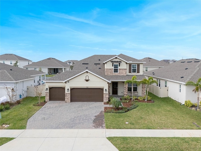 traditional-style home with stone siding, decorative driveway, a front yard, and a residential view