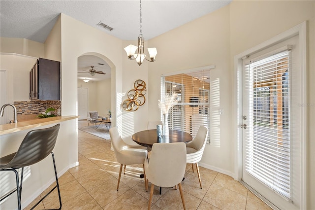 tiled dining space with ceiling fan with notable chandelier, sink, and a textured ceiling