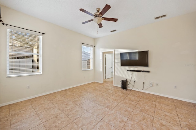 unfurnished living room featuring ceiling fan, vaulted ceiling, a textured ceiling, and light tile patterned floors