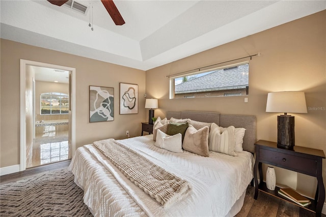 bedroom with ceiling fan, dark hardwood / wood-style flooring, and a tray ceiling