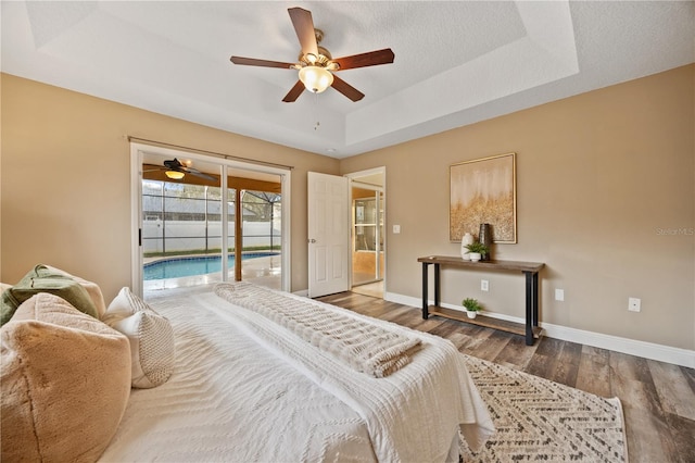 bedroom with ceiling fan, wood-type flooring, a tray ceiling, and access to outside