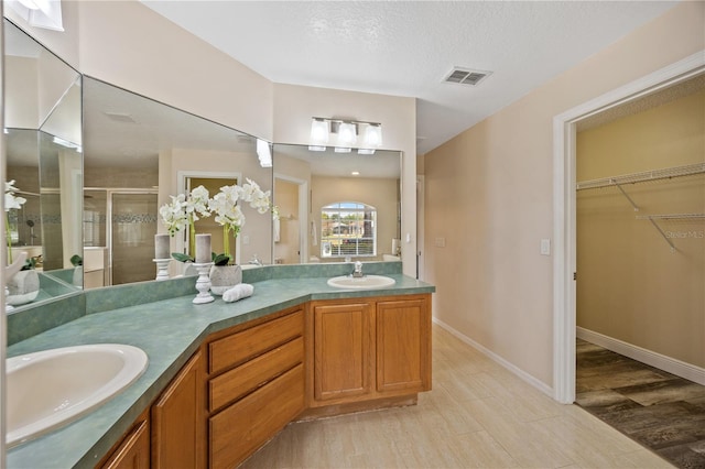 bathroom with hardwood / wood-style flooring, vanity, a textured ceiling, and a shower with shower door