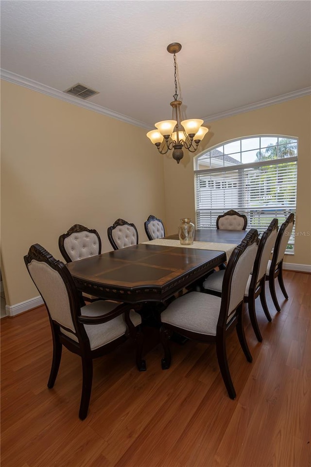 dining space featuring crown molding, hardwood / wood-style floors, and a notable chandelier