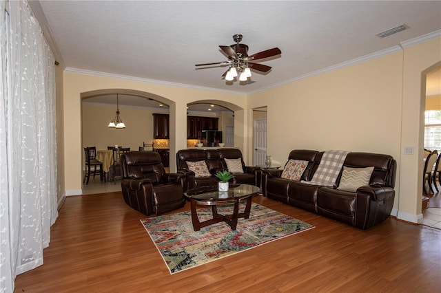 living room featuring wood-type flooring, ornamental molding, a textured ceiling, and ceiling fan