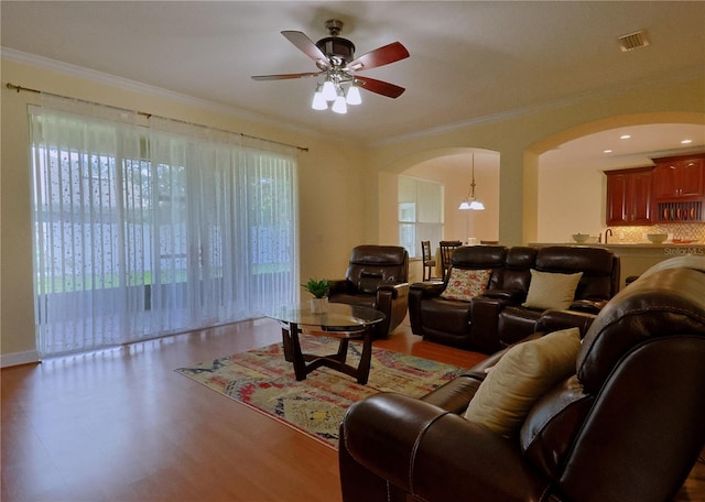 living room featuring crown molding, ceiling fan, and light wood-type flooring