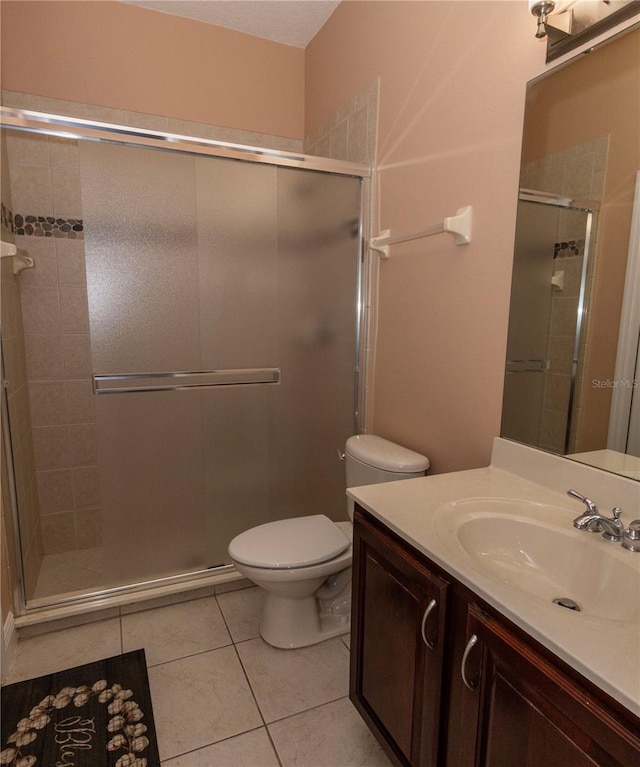 bathroom with tile patterned floors, toilet, a shower with door, and vanity