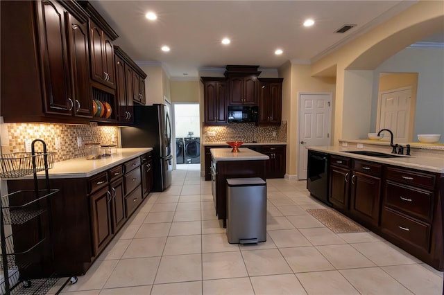 kitchen featuring separate washer and dryer, sink, dark brown cabinets, and black appliances