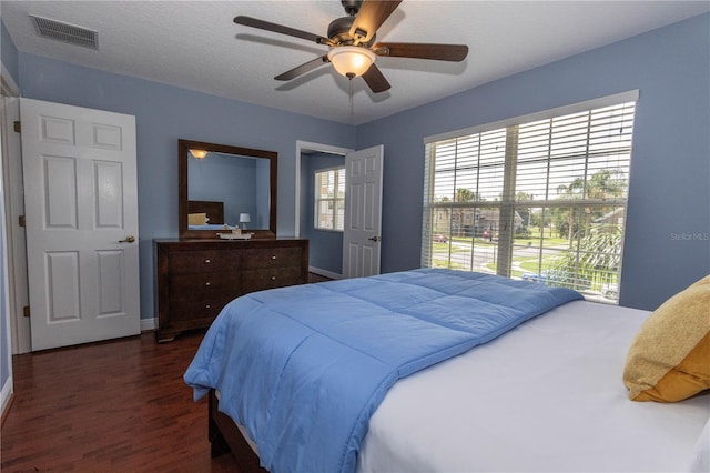 bedroom with ceiling fan, dark wood-type flooring, and a textured ceiling