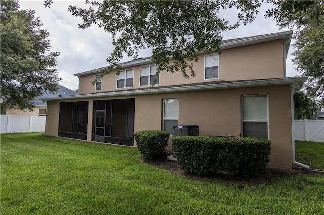 rear view of house featuring cooling unit, a sunroom, and a lawn