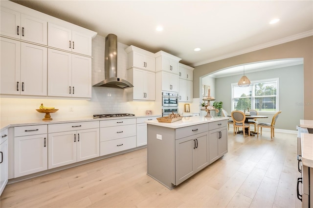 7515 John Hancock Dr, Winter Garden, FL 34787 - kitchen featuring tasteful backsplash, ornamental molding, wall chimney range hood, light countertops, and arched walkways