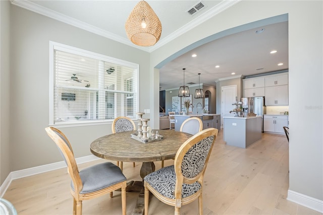 7515 John Hancock Dr, Winter Garden, FL 34787 - dining area with arched walkways, light wood finished floors, visible vents, and crown molding
