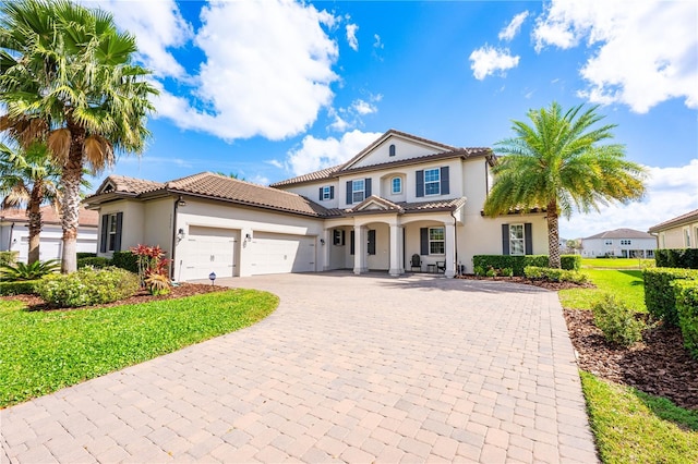 7515 John Hancock Dr, Winter Garden, FL 34787 - mediterranean / spanish house with a tiled roof, a garage, stucco siding, a front lawn, and decorative driveway