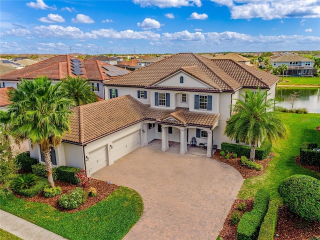 mediterranean / spanish home with decorative driveway, stucco siding, an attached garage, a residential view, and a tiled roof