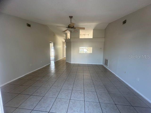 unfurnished room featuring lofted ceiling, light tile patterned floors, ceiling fan, and visible vents