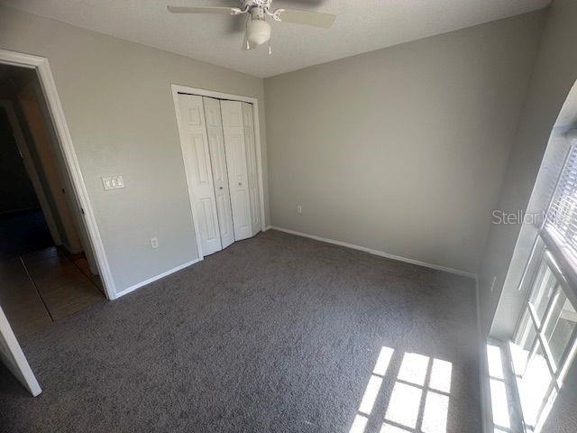 unfurnished bedroom with carpet floors, a closet, ceiling fan, and baseboards