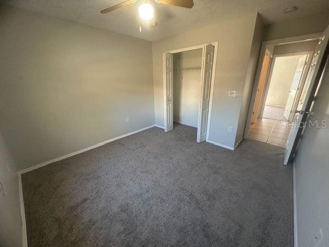 unfurnished bedroom featuring a ceiling fan, a closet, carpet flooring, and baseboards