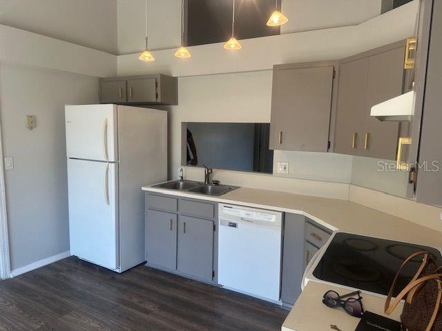 kitchen with light countertops, white appliances, a sink, and gray cabinetry