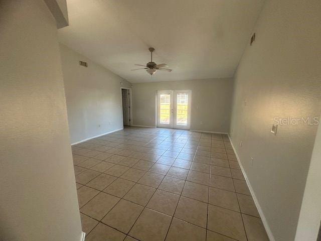 empty room featuring ceiling fan, light tile patterned flooring, baseboards, vaulted ceiling, and french doors