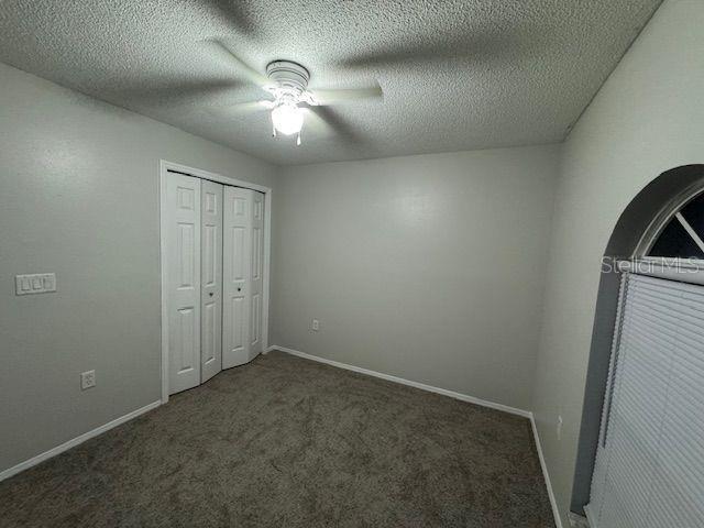 unfurnished bedroom featuring a textured ceiling, carpet flooring, and baseboards