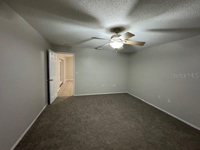 spare room with carpet floors, ceiling fan, baseboards, and a textured ceiling