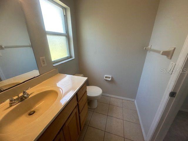 bathroom with toilet, vanity, baseboards, and tile patterned floors