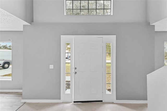 entryway featuring a healthy amount of sunlight, baseboards, and light tile patterned floors