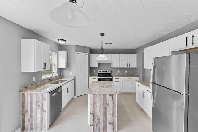 kitchen featuring a kitchen island, decorative light fixtures, stainless steel appliances, white cabinetry, and a sink