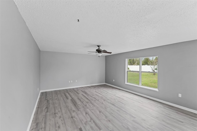 empty room featuring light wood-style floors, a textured ceiling, baseboards, and a ceiling fan