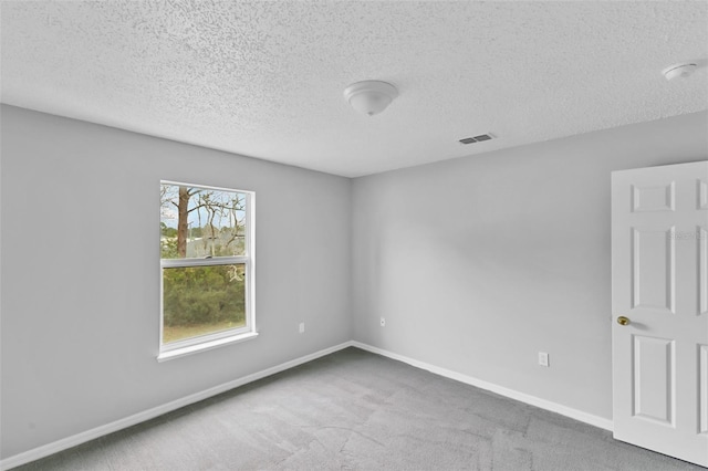 carpeted empty room with a textured ceiling, visible vents, and baseboards