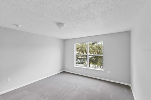 carpeted spare room with baseboards and a textured ceiling