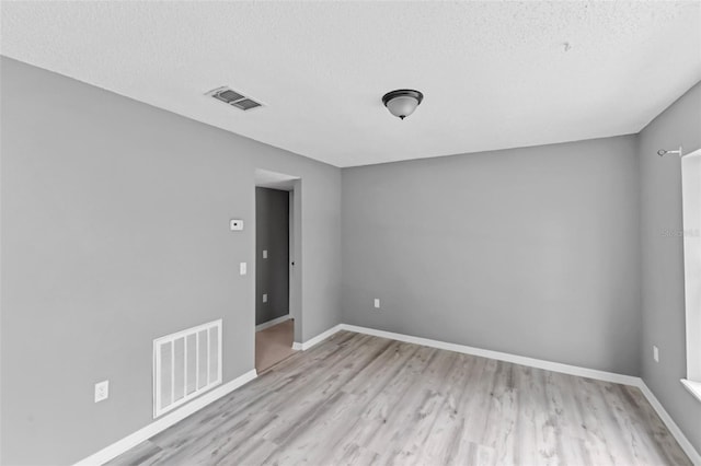 unfurnished room with light wood-style floors, visible vents, and baseboards