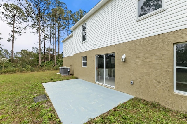 back of property featuring a patio, central AC unit, a lawn, and stucco siding