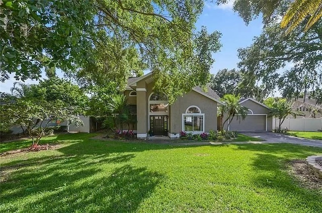 view of front facade featuring aphalt driveway, a front yard, an attached garage, and stucco siding