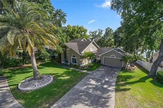 view of front of house with stucco siding, concrete driveway, a front yard, fence, and a garage