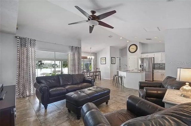 living room with ceiling fan with notable chandelier and high vaulted ceiling