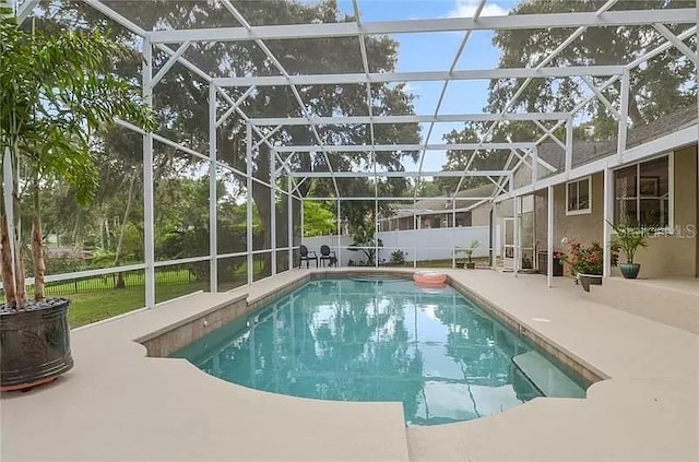 view of swimming pool featuring glass enclosure, a patio area, fence, and a fenced in pool