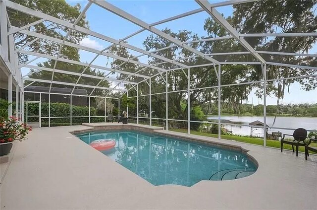 pool with a patio, a water view, and a lanai