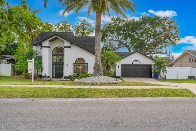 view of front of home featuring fence, an attached garage, concrete driveway, a front lawn, and stucco siding